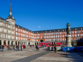 Group of people in front of building against blue sky