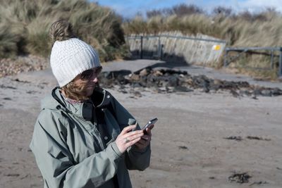 Woman using smart phone while standing at field