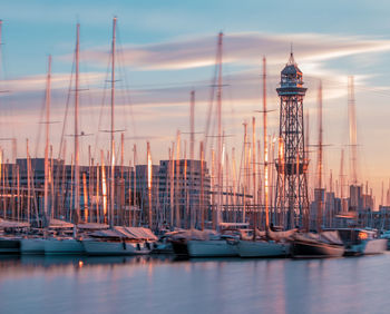 Sailboats in sea at harbor against sky during sunset