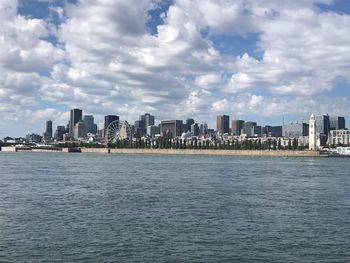 Sea by buildings against sky in city