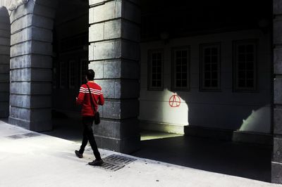 Rear view of woman standing by building