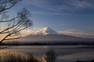 Scenic view of lake by snowcapped mountains against sky during sunset