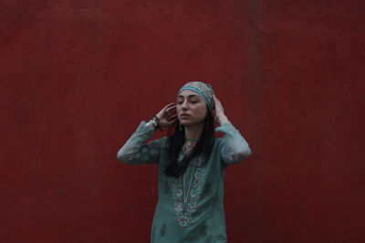 Young woman standing against red wall