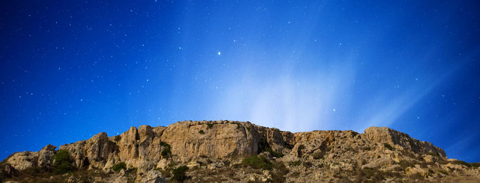 Low angle view of mountain against blue sky