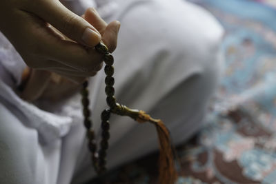 Close-up of hand holding cross against blurred background