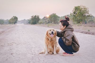 Young woman touching dog during sunset