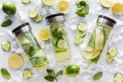Glass bottles of cucumber water with lime and mint mixed in.