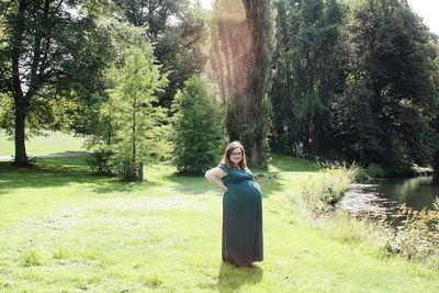 Portrait of smiling pregnant woman standing on land in park