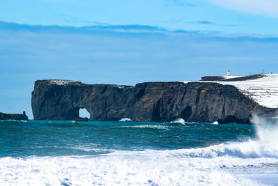 Rock formations by sea against blue sky