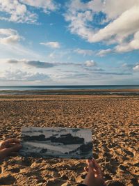 Cropped hands holding photograph against beach