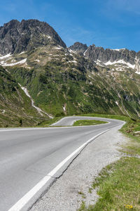 Road by mountains against sky