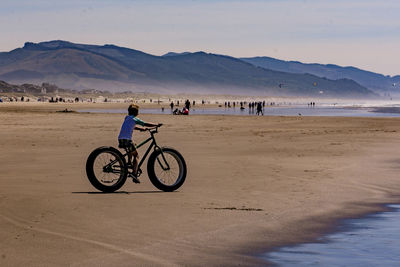 Boy riding bicycle on beach