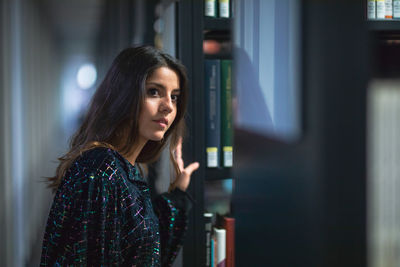 Portrait of young woman standing in library