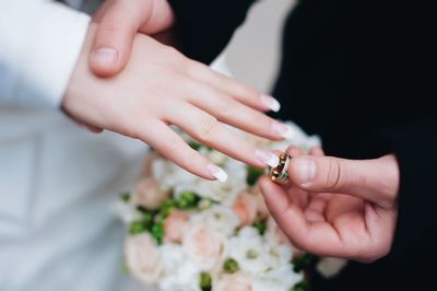 Groom putting ring in finger of bride