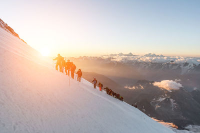 People on snowcapped mountain against sky