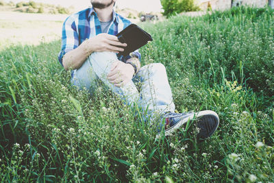 Midsection of man using mobile phone in field