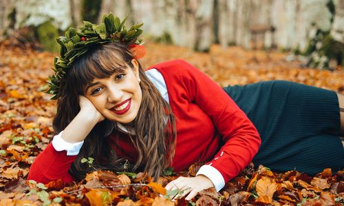 Portrait of young woman lying down on autumn leaves