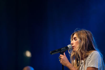 Midsection of woman holding umbrella against blue sky