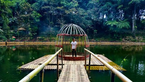 Man standing on footbridge over lake