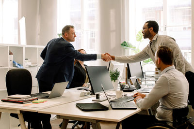 Businessmen shaking hands during sales meeting in office