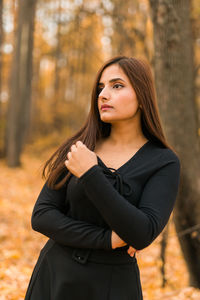 Portrait of young woman standing against trees