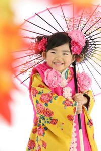 Cute girl holding umbrella while wearing kimono