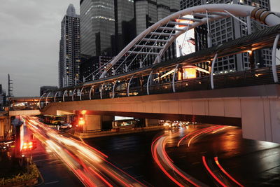 High angle view of light trails on road amidst buildings in city at night