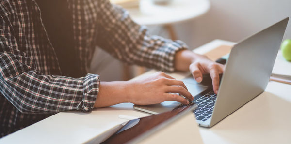 Midsection of man using laptop on table