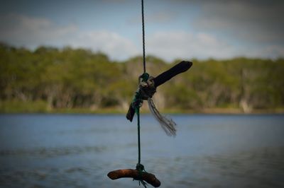 Sticks tied on string hanging over lake