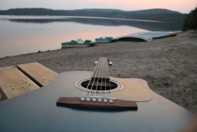 Close-up of guitar at beach at dusk