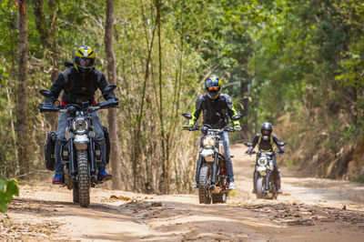 Three friends riding their scrambler motorcycles through forrest