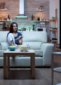 Portrait of smiling young woman sitting on sofa at home