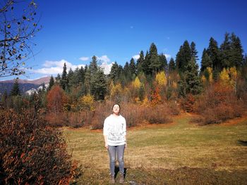 Man standing by trees against sky during autumn