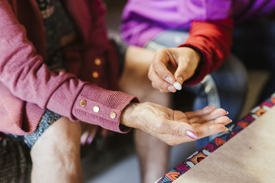 Caregiver giving medicine to senior woman at home