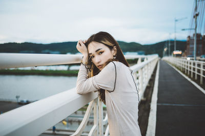 Portrait of young woman standing on railing