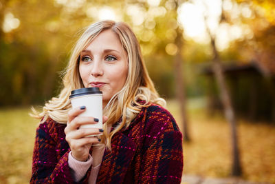 Portrait of young woman using mobile phone in park