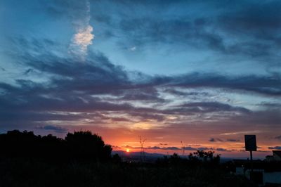 Silhouette trees against dramatic sky during sunset