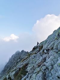 Low angle view of people on rock against sky