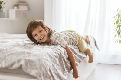 Adorable boy indulges on the bed, smiles and looks into the camera. children at home. rest