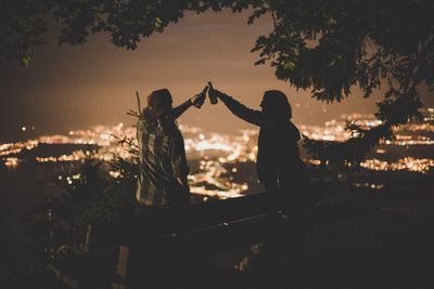 Friends toasting bottles in city against sky