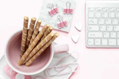 A feminine workspace, keyboard of a computer on pink background with copy space