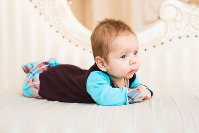 Portrait of cute baby lying on bed at home