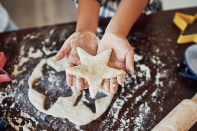 Cropped hand of person preparing gingerbread cookies