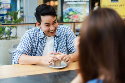 Midsection of man sitting on table at cafe