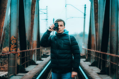 Young man photographing while standing on railing