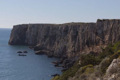 Rock formations by sea against clear sky