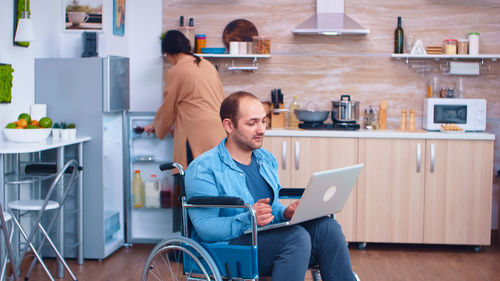 Side view of young woman using laptop while sitting in cafe