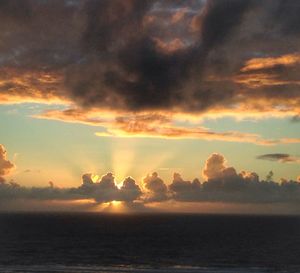 Scenic view of sea against cloudy sky at sunset