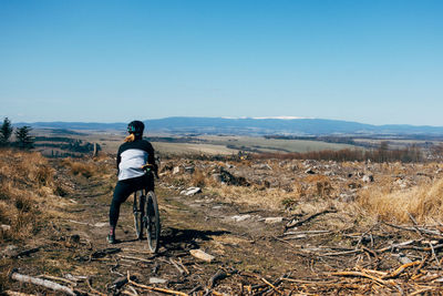 Rear view of man riding on landscape against clear sky