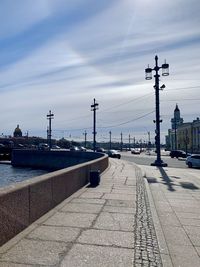 Footpath by street against sky in city